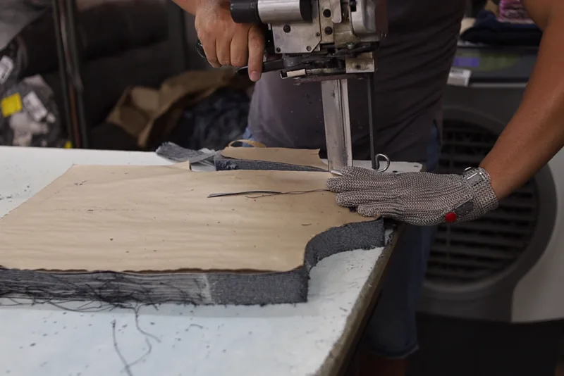 Máquina de corte sobre o enfesto de jeans